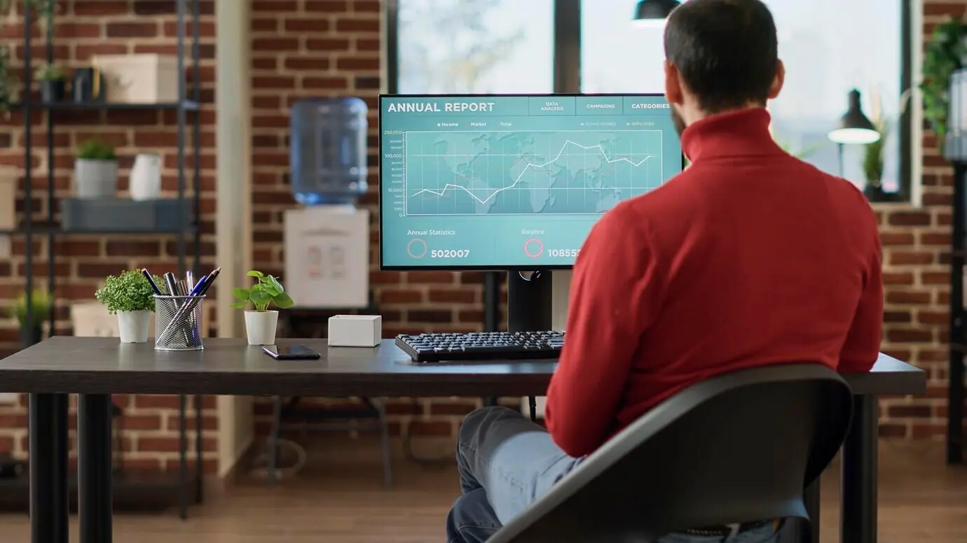 Менеджер проекта смотрит на компьютер с графиками форекс, работает с финансовой статистикой, данными о продажах и инвестициями проекта. Торговый аналитик использует тренды и индексы фондового рынка.